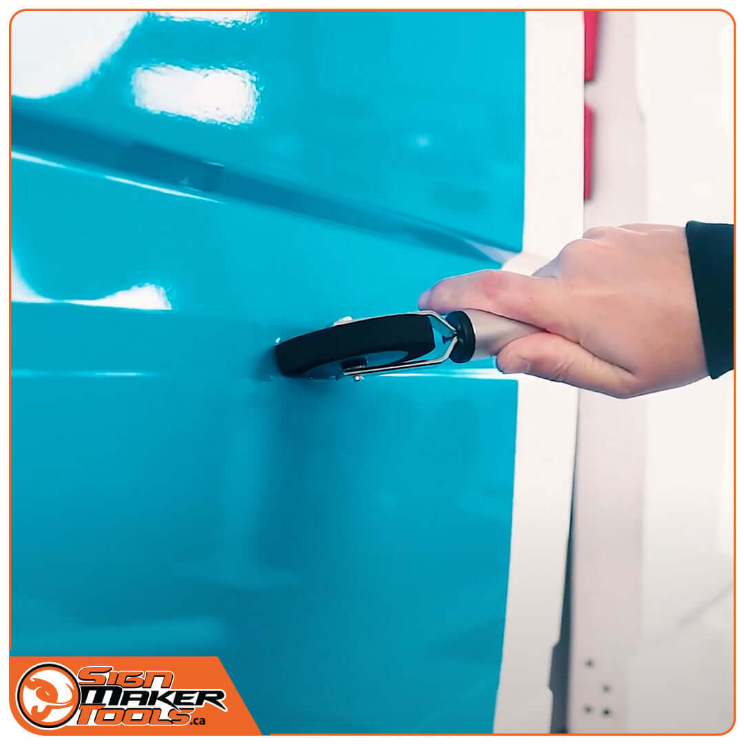 Close-up of Yellotools pressure roller in use on blue sign substrate