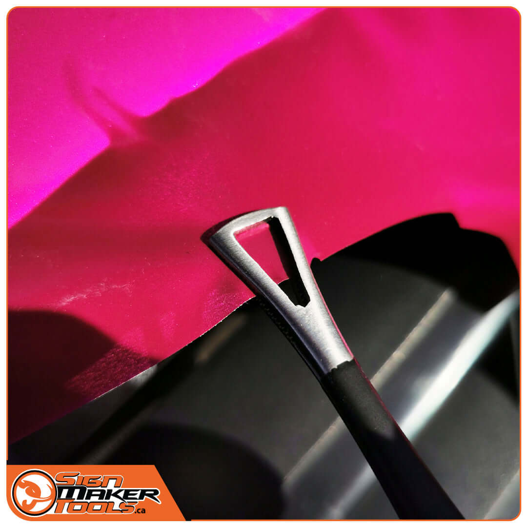 Spade-shaped tip of the WrapTweezer tweezers gripping pink car wrap film