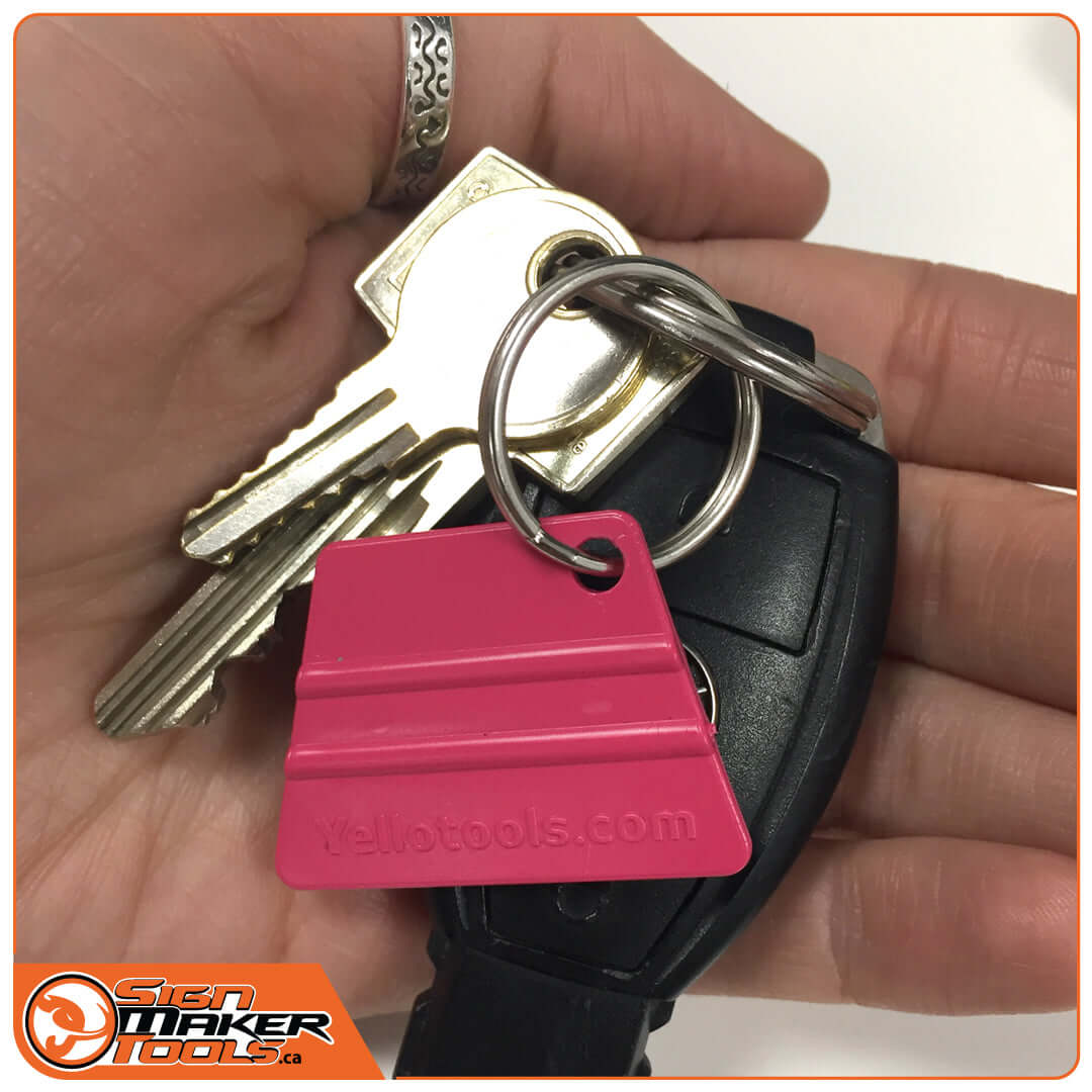 Pink mini squeegee keychain attached to a set of keys in a person's hand