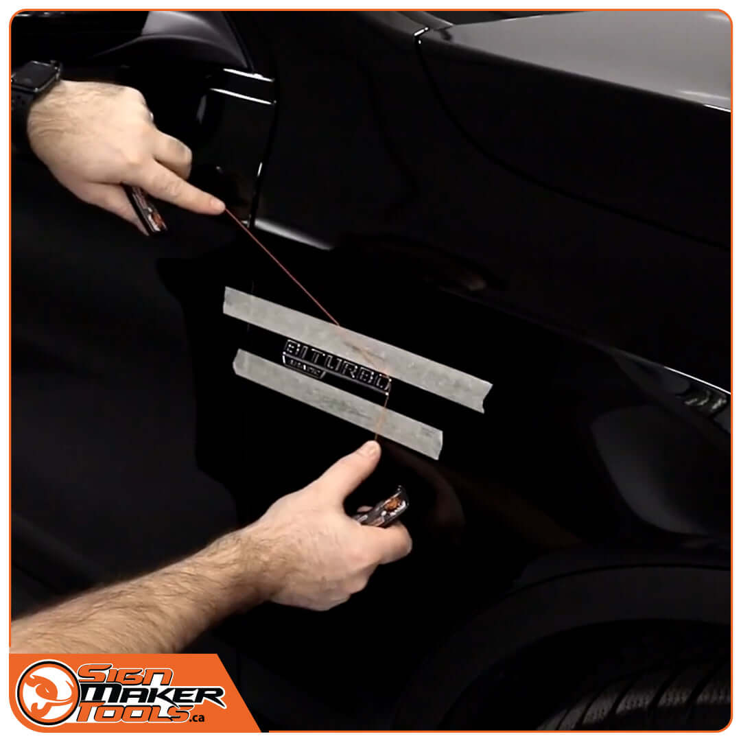 Using PlateLine Remover to take off a car emblem from a black vehicle door