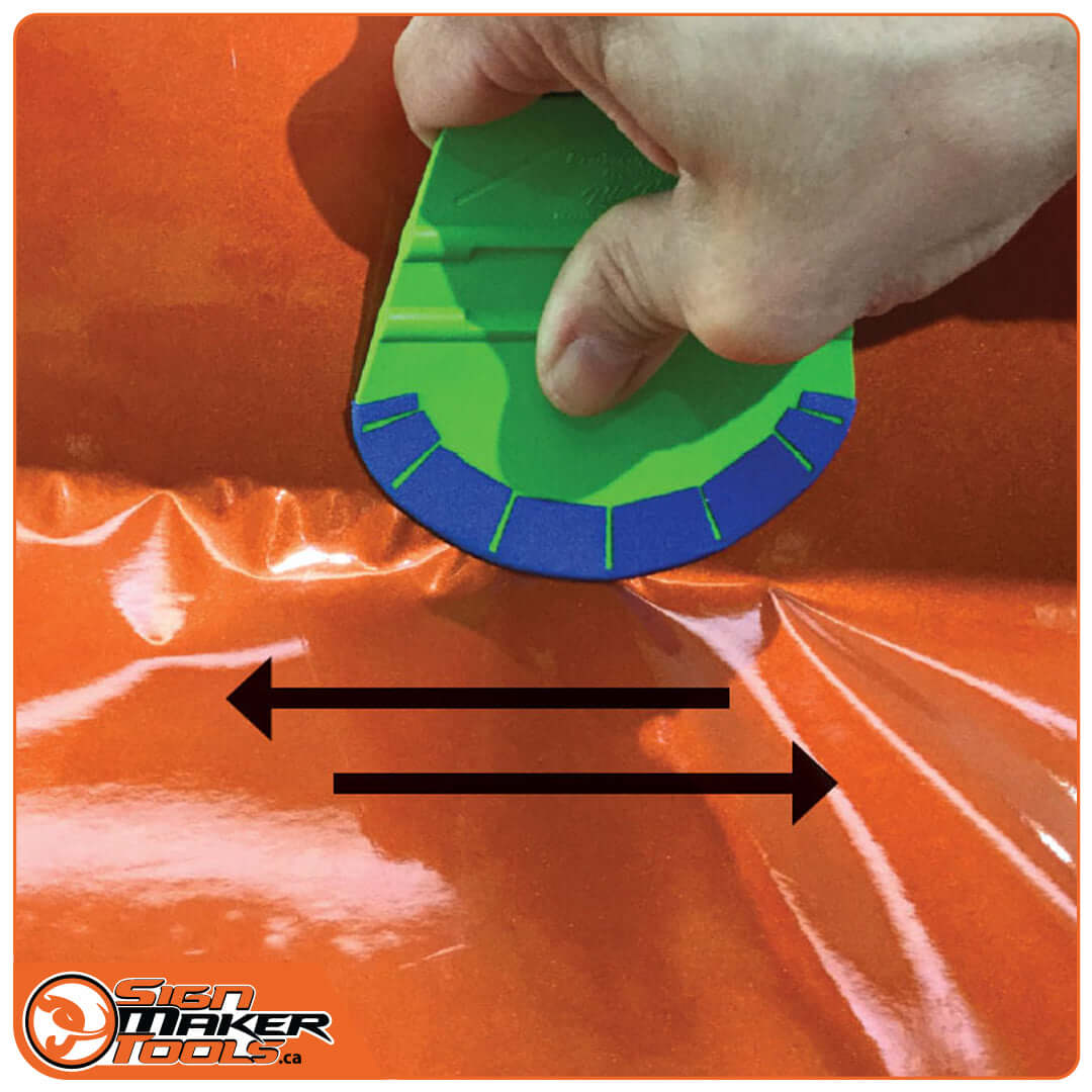 Applying car wrap film with green ProWrap Betty squeegee on orange surface