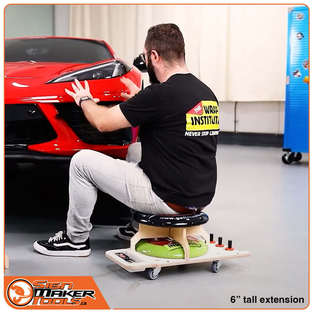 Installer using the LowRider seat to apply vehicle graphics to a red sports car