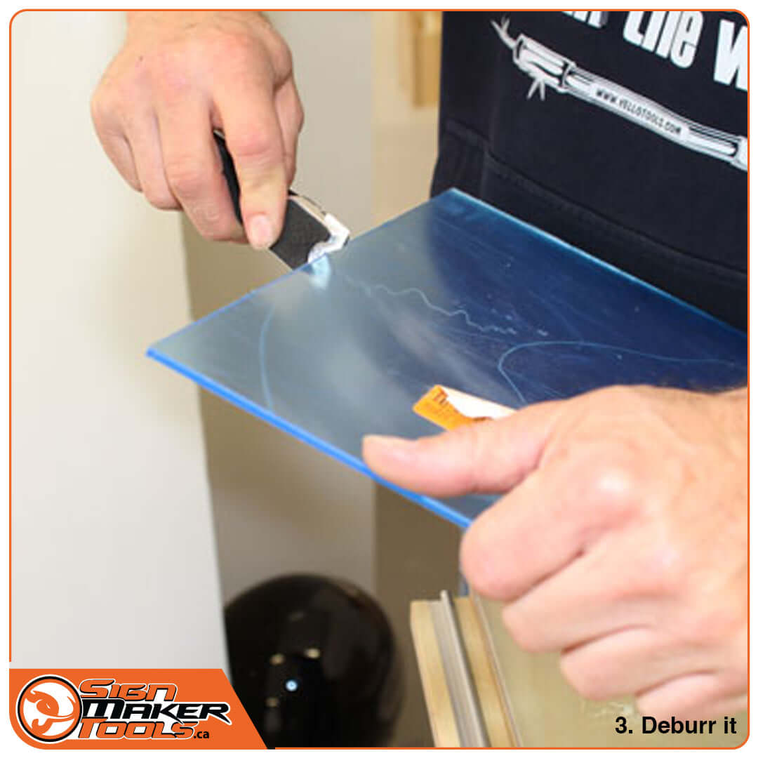 Close-up of hand using P-Glass Twin tool to deburr the edge of a plexiglass sheet