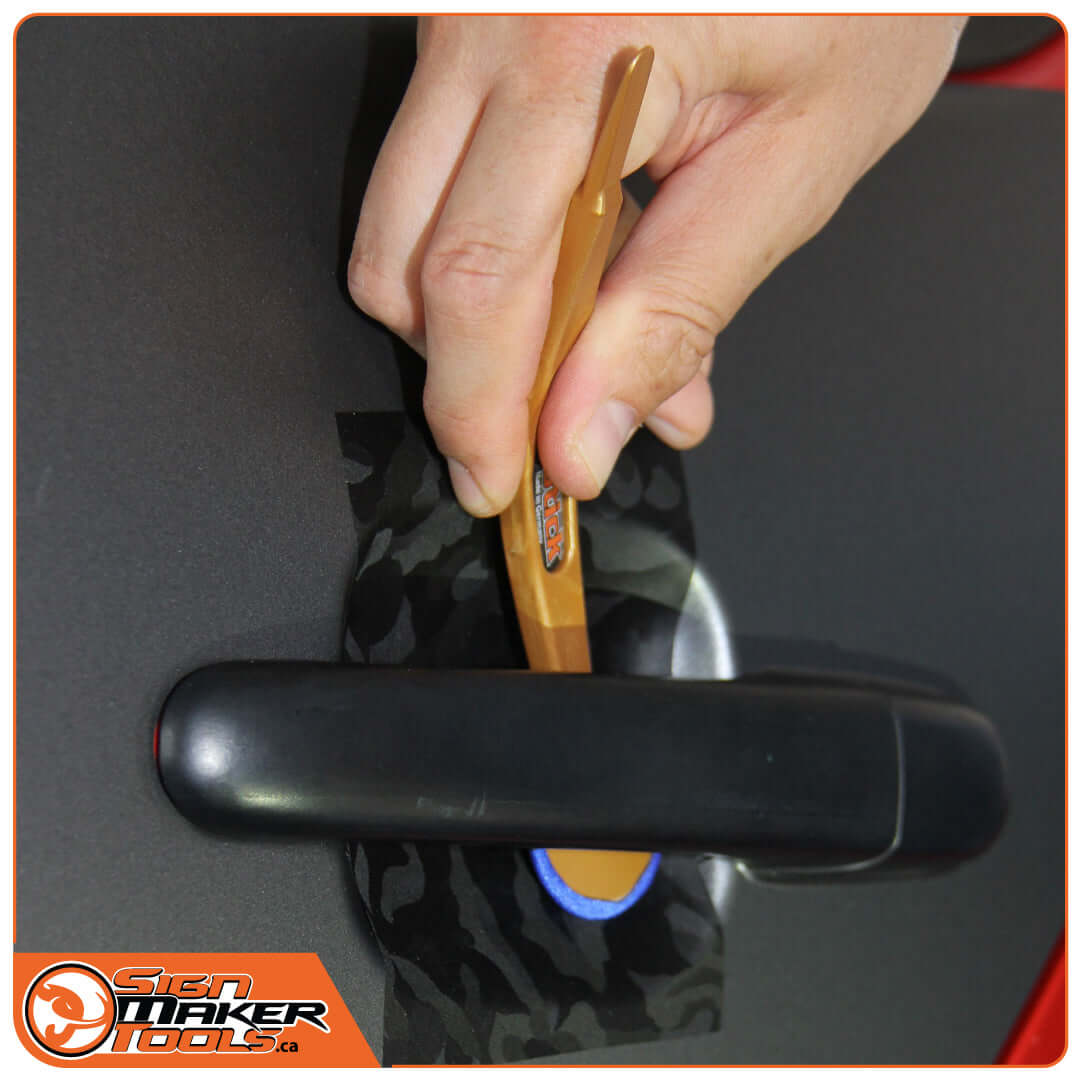 Hand inserting WrapStick Betty under a car door handle for precise vinyl application