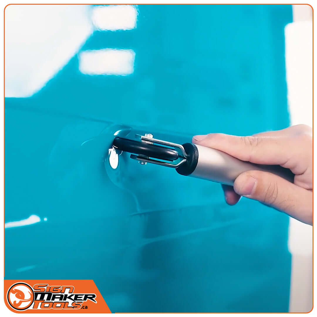 Hand using a pressure roller for smoothing wrap film into deep vehicle grooves