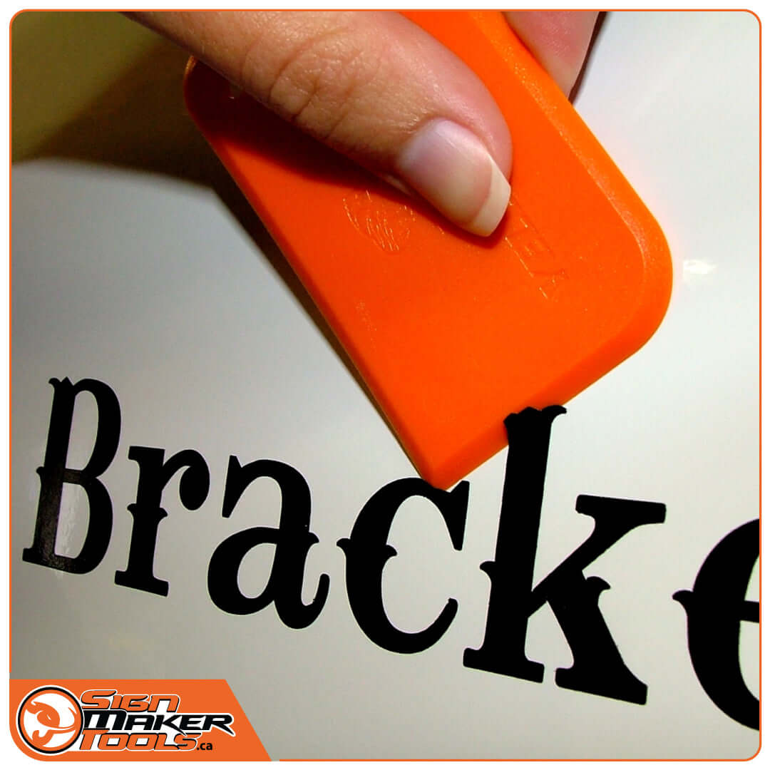Using the orange YelloBlade scraper to lift vinyl lettering from a surface