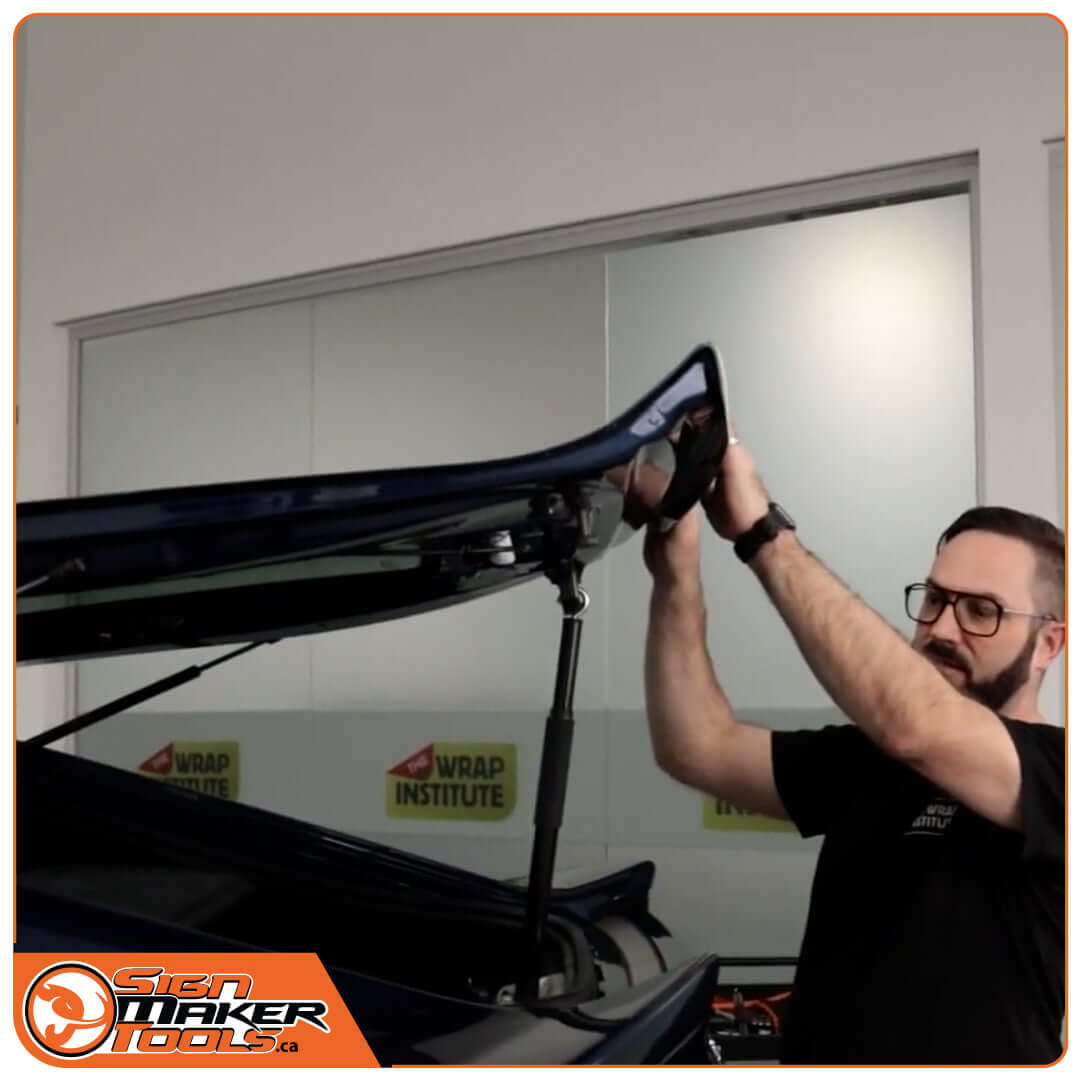 Person using YelloOpen tool to secure an open car trunk for easy access