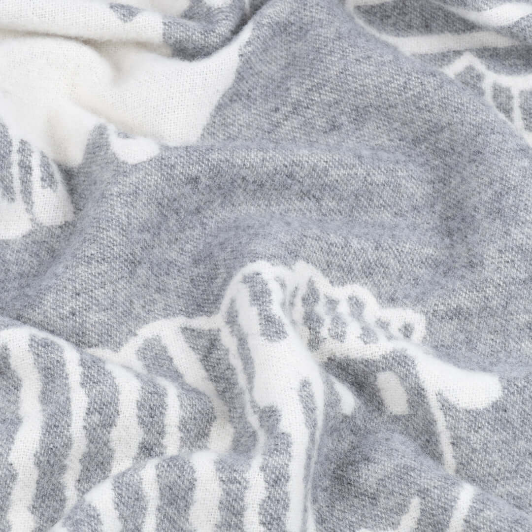 Close-up of soft wool fabric in grey and white, showcasing detailed sheep pattern