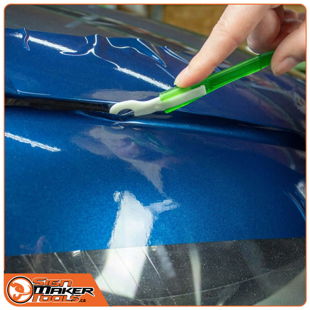 WrapDefender tool safely trimming vinyl wrap along a car's hood edge