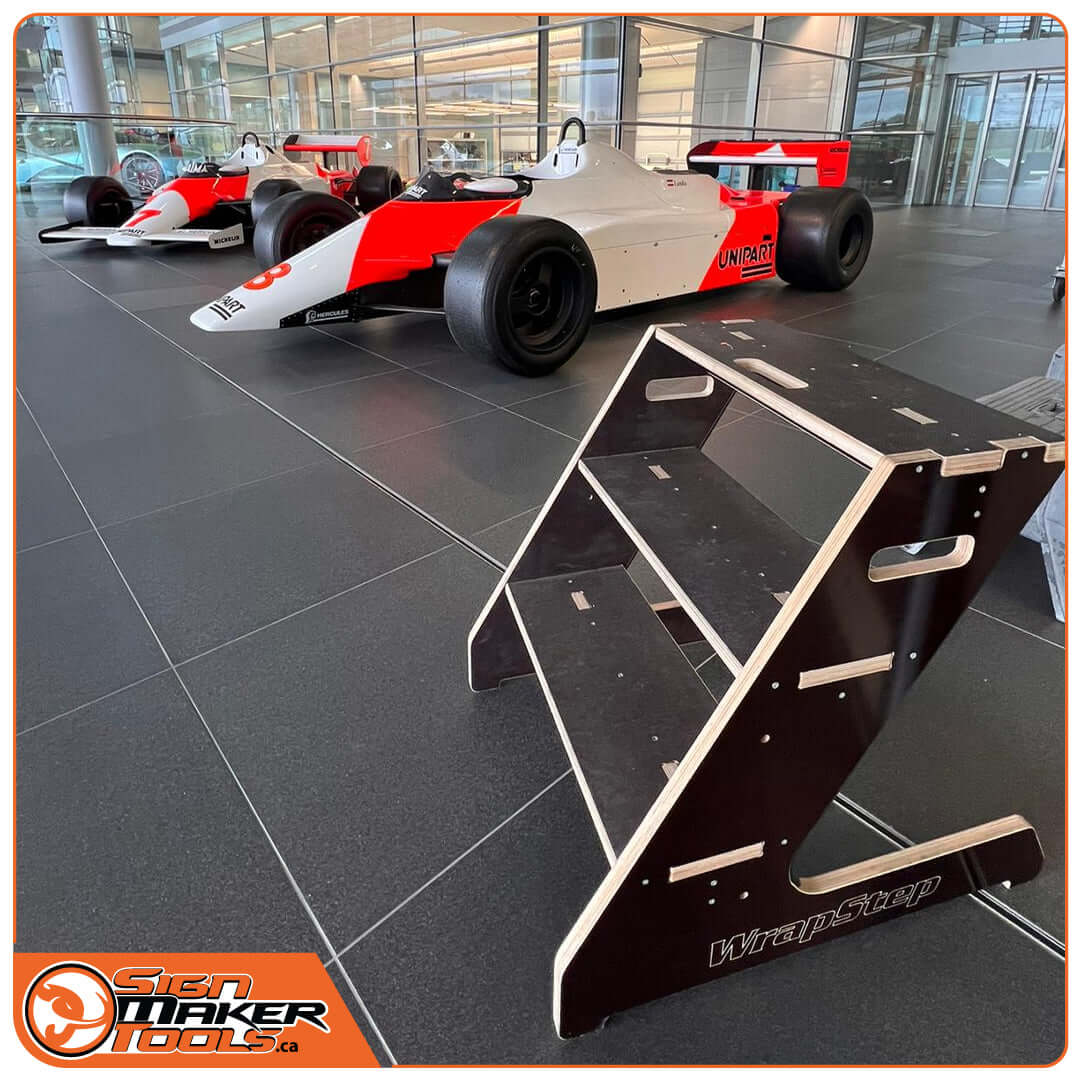 WrapStep ladder showcased next to race cars in a modern showroom