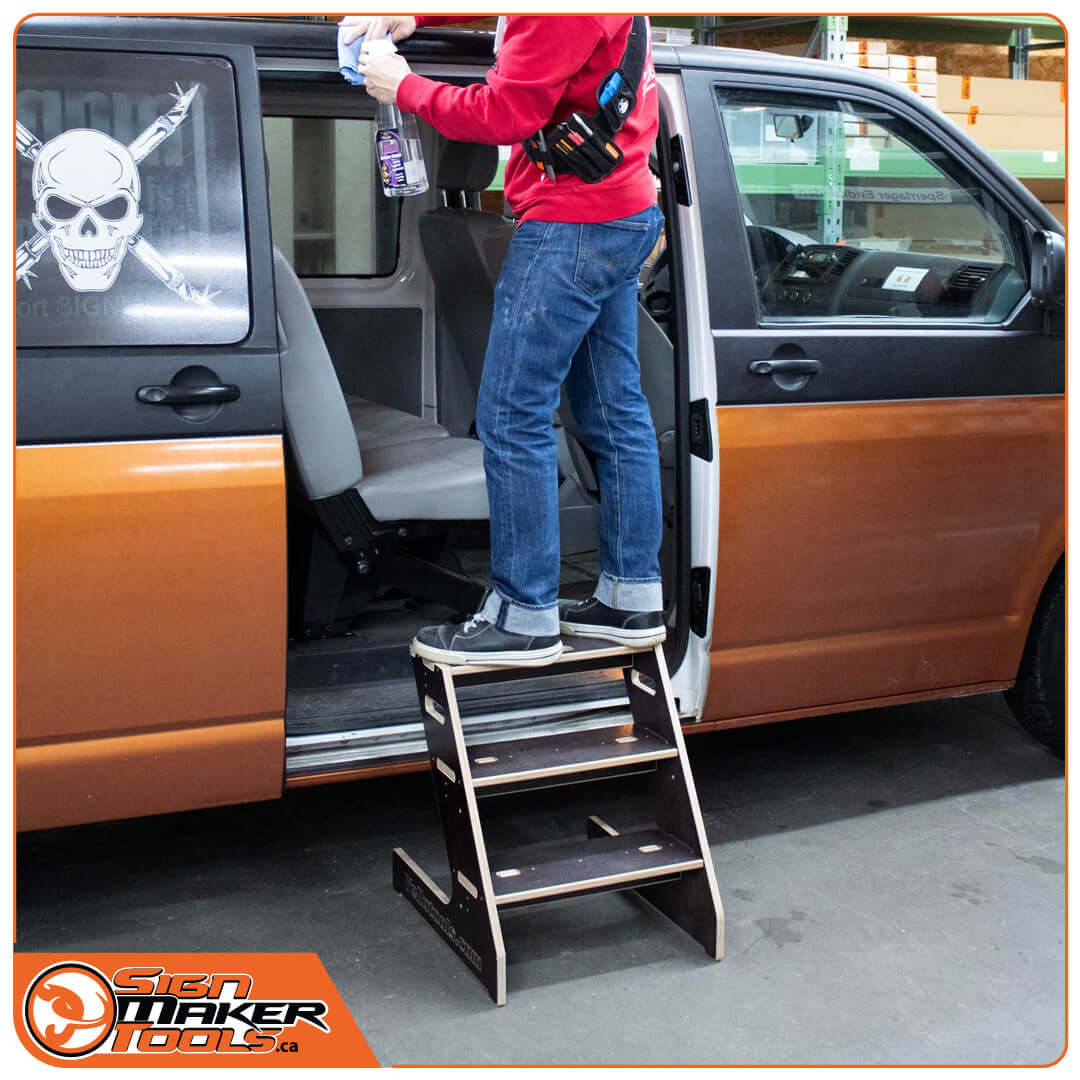 Person using WrapStep ladder to access a vehicle during wrapping process